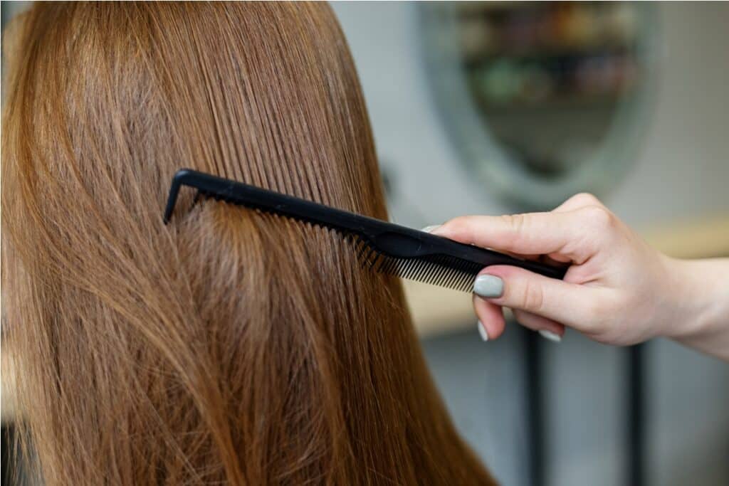 a woman in a barber shop combs her long hair.