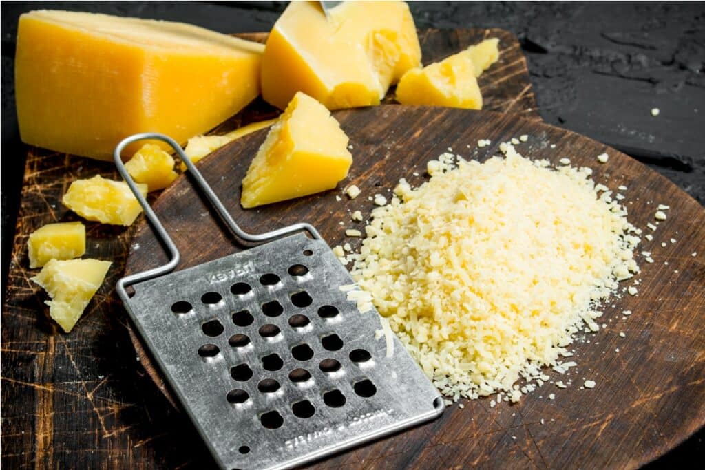 grated parmesan cheese on a wooden board. on black rustic background.