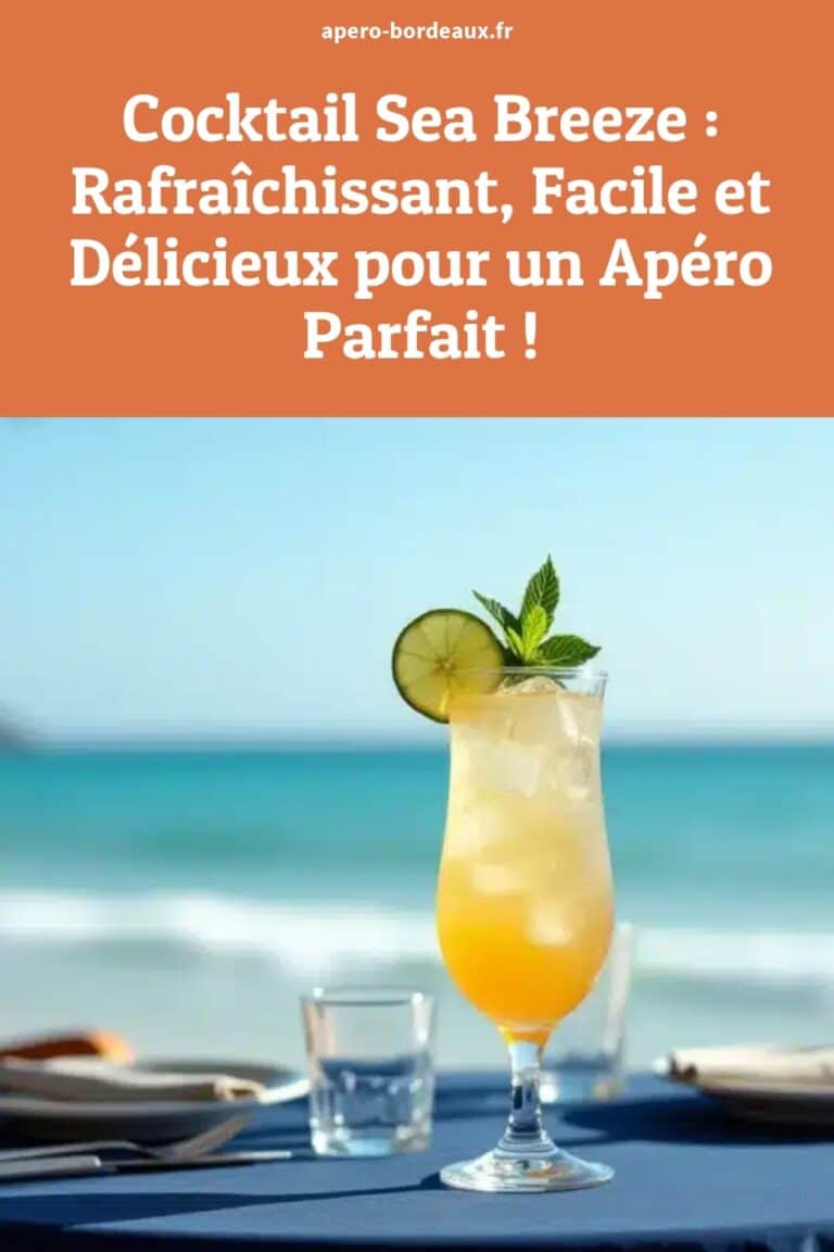 Verre de cocktail Sea Breeze orange garni d'une tranche de citron vert et de feuilles de menthe sur une table face à l'océan, parfait pour un apéritif rafraîchissant.