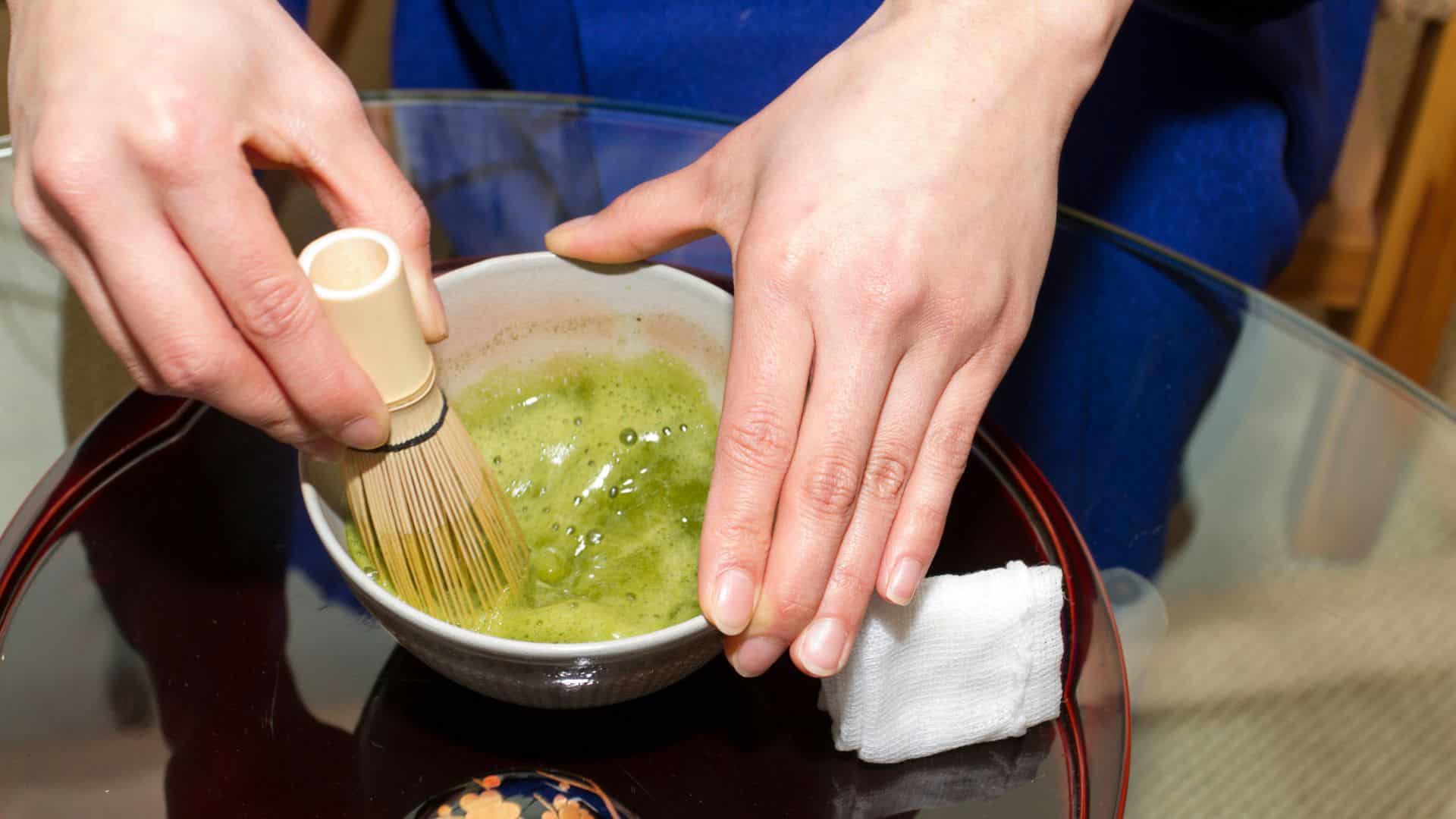 Préparation du thé matcha avec un fouet traditionnel.