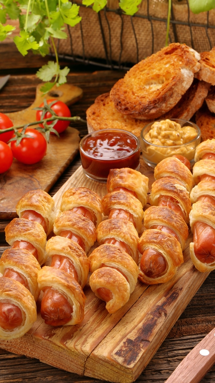 Saucisses enroulées de pâte feuilletée sur planche.