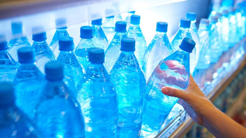 Main tenant une bouteille d'eau en rayon.