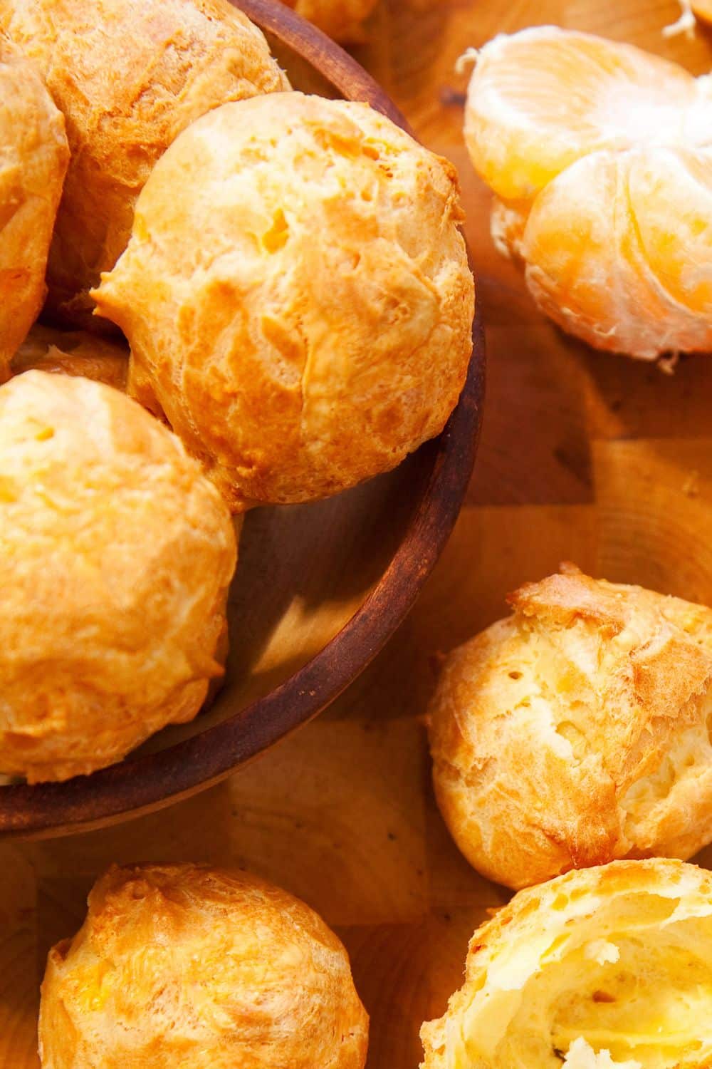 Gougères dorées servies avec des quartiers de clémentine.
