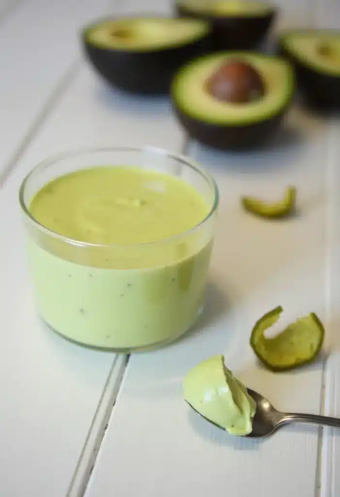 Crème d'avocat dans un verre sur table blanche.