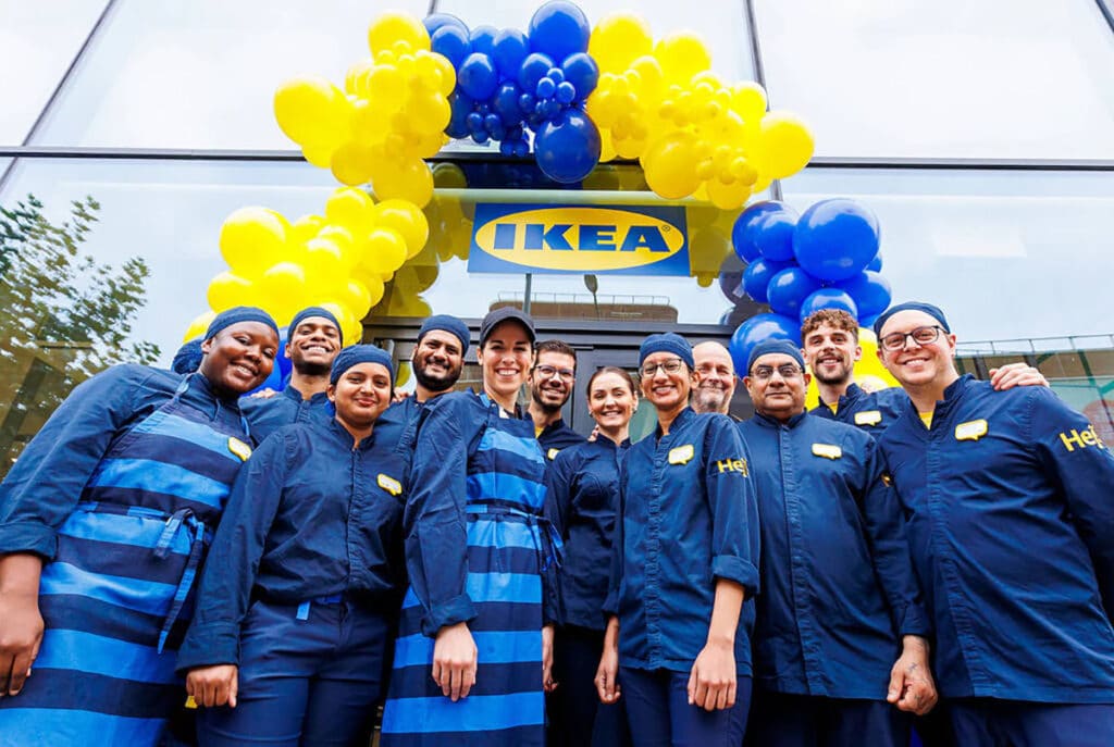 Équipe souriante devant magasin IKEA avec ballons.