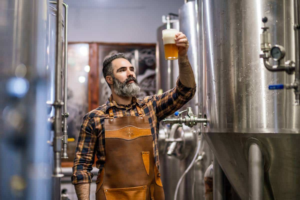 Brasseur inspectant une bière artisanale en cuverie.