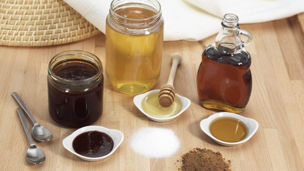 Miels et sirop présentés avec cuillères.