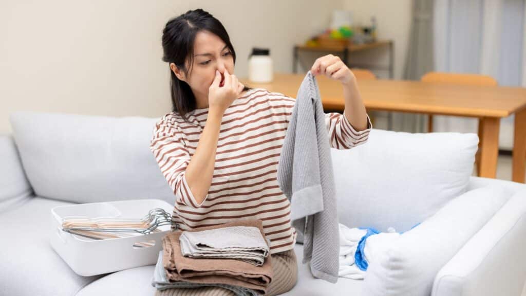 Femme sentant un pull avec dégoût.