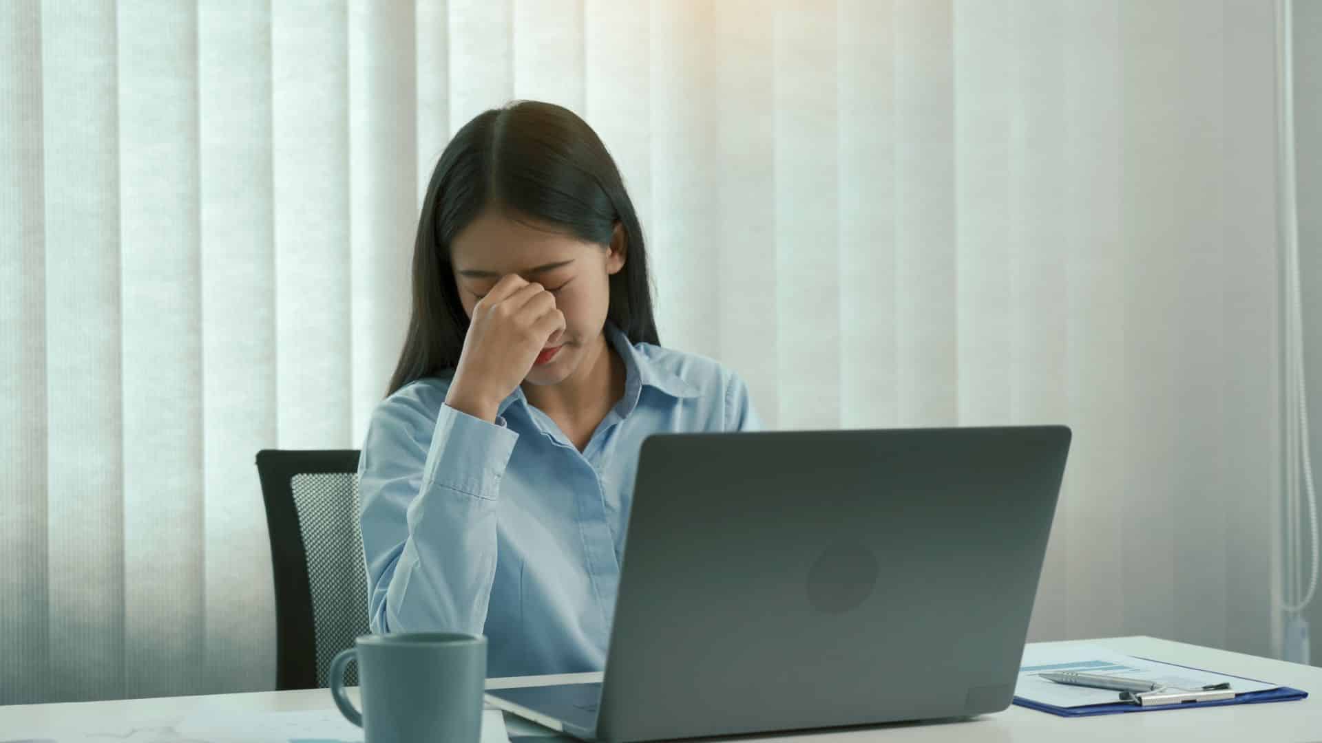 Femme fatiguée devant son ordinateur au bureau.