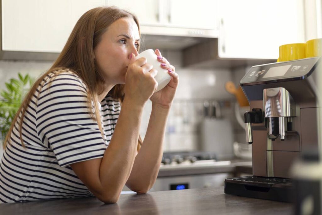 Femme buvant du café près d'une cafetière.