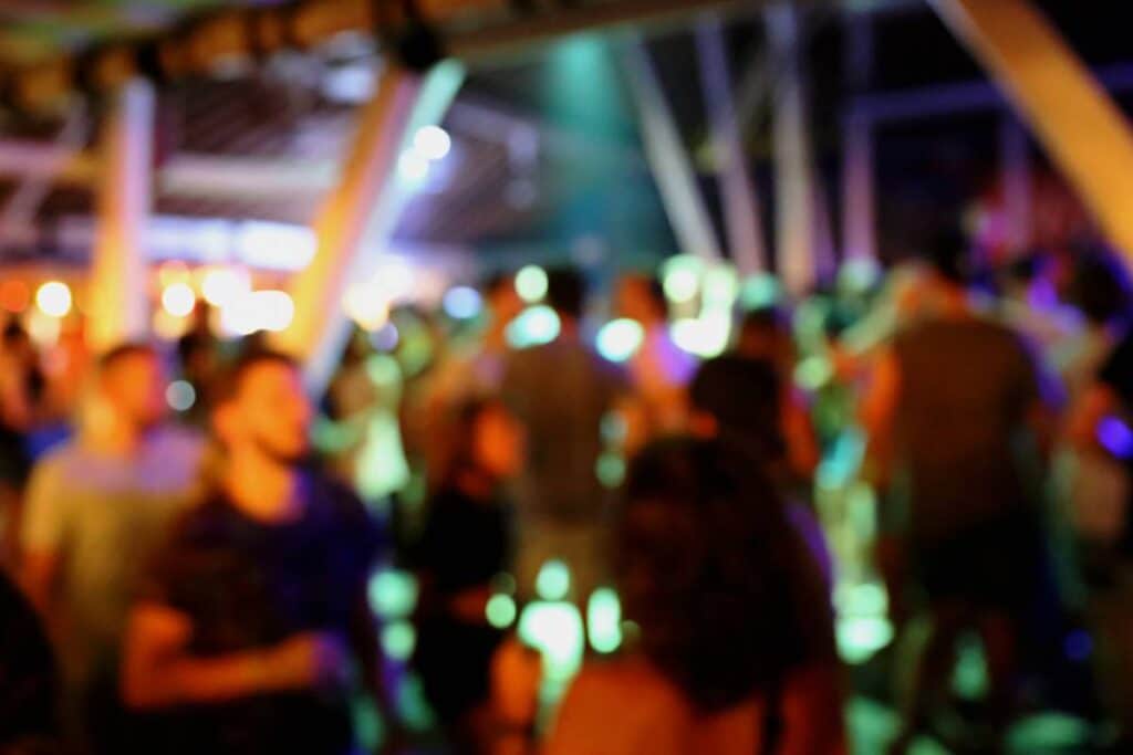 Foule floue avec lumières colorées en soirée.