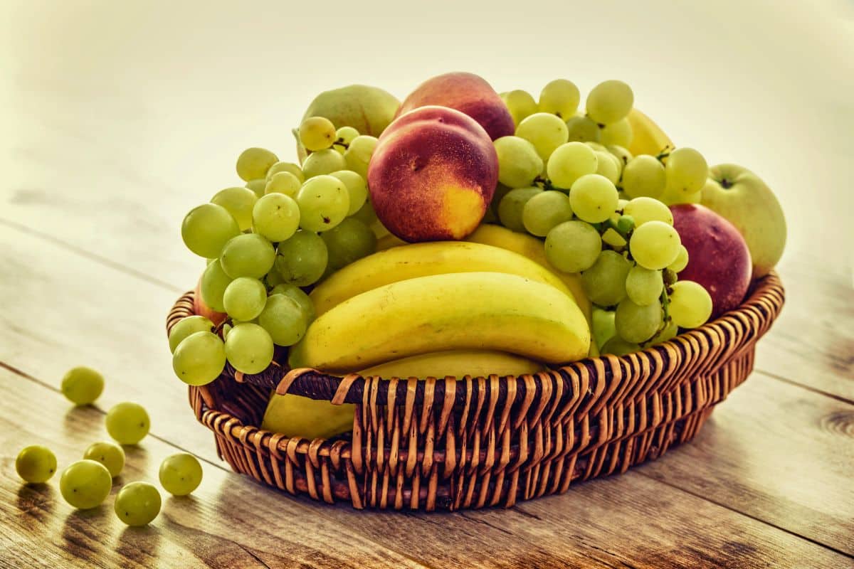 Corbeille de fruits : raisins, bananes, pêches.