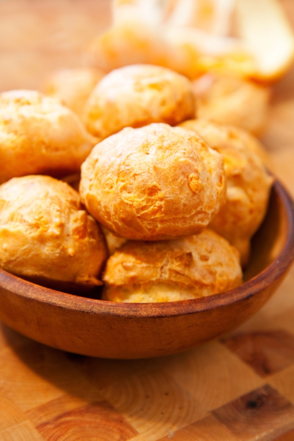 Bol de gougères dorées sur table en bois.
