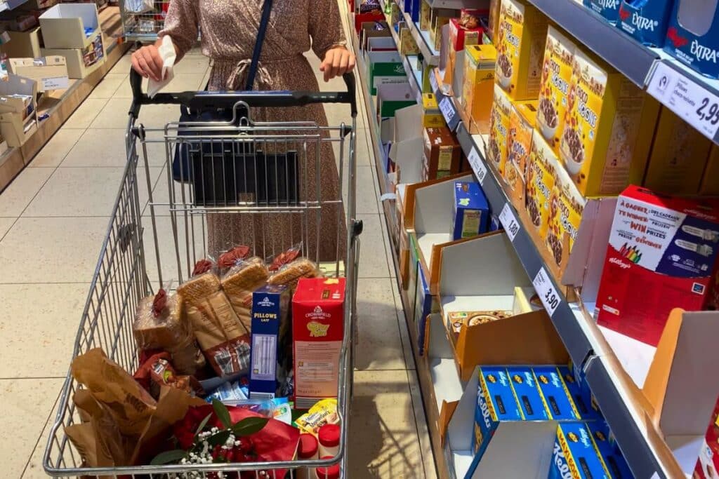 Personne poussant un chariot plein dans un supermarché