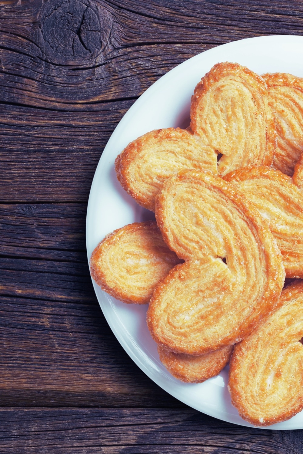 Assortiment de palmiers feuilletés sur une assiette blanche.