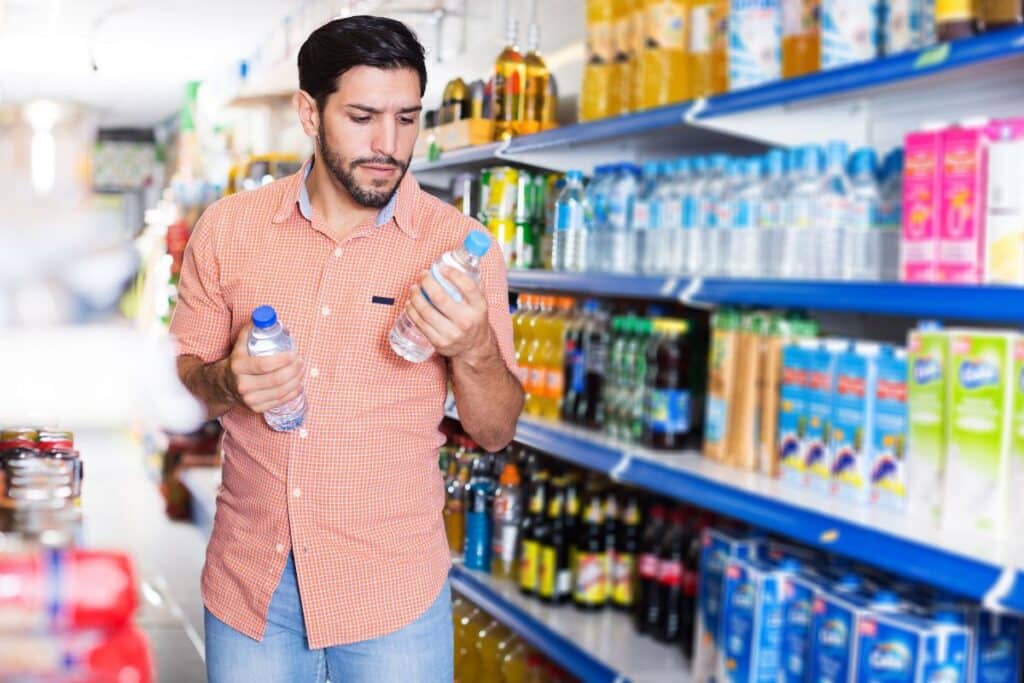 Homme choisissant des bouteilles d'eau au supermarché.