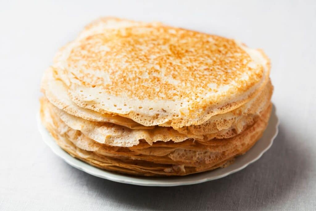 Pile de crêpes sur une assiette blanche.