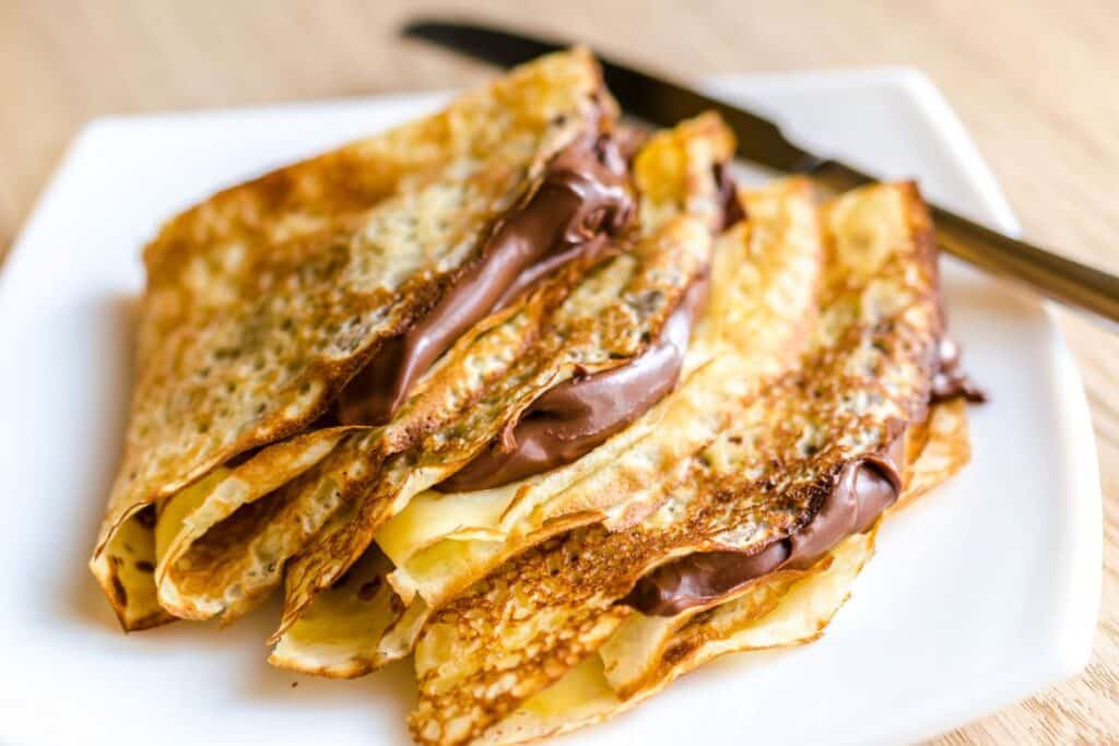 Crêpes au chocolat sur une assiette blanche.