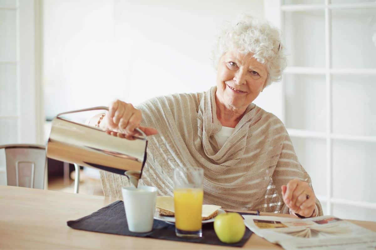Femme âgée verse du thé en souriant