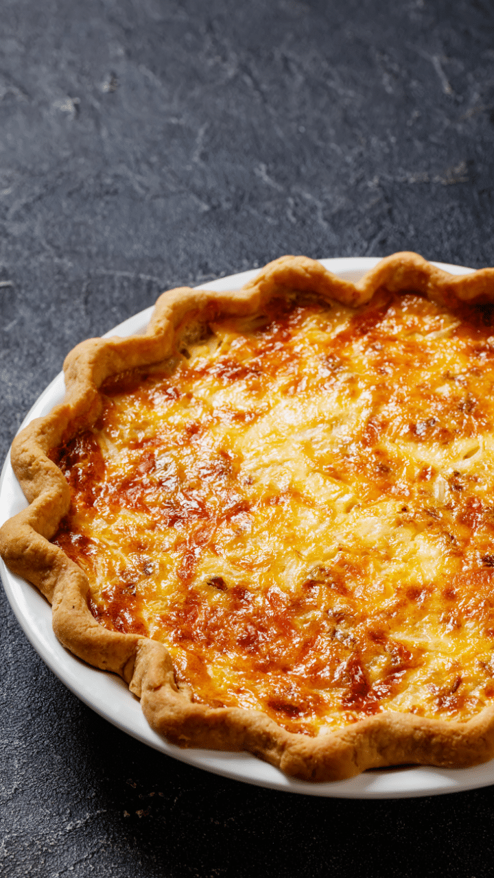 Quiche avec croûte dorée sur assiette blanche.