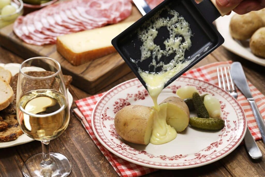 Raclette fromage fondu sur pommes de terre avec vin blanc.