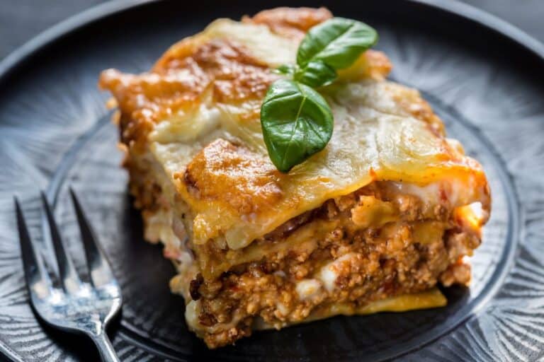 Lasagne bolognaise avec basilic sur assiette noire.