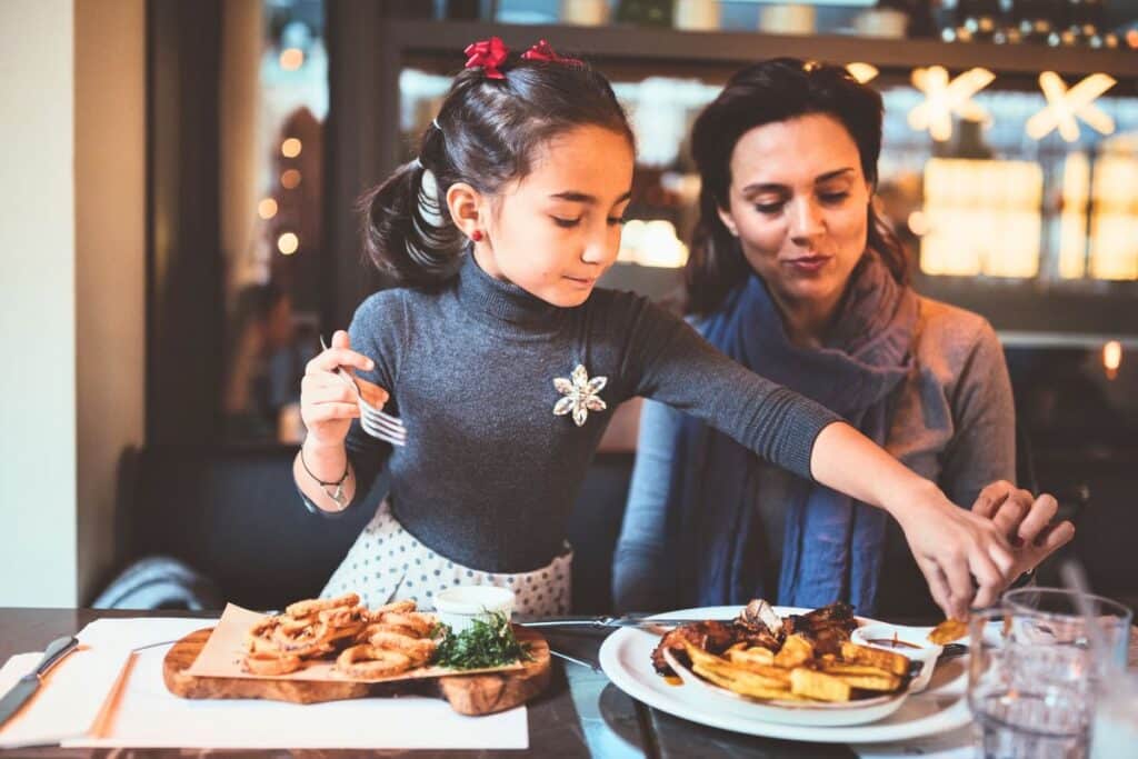 Enfant et adulte mangeant au restaurant.