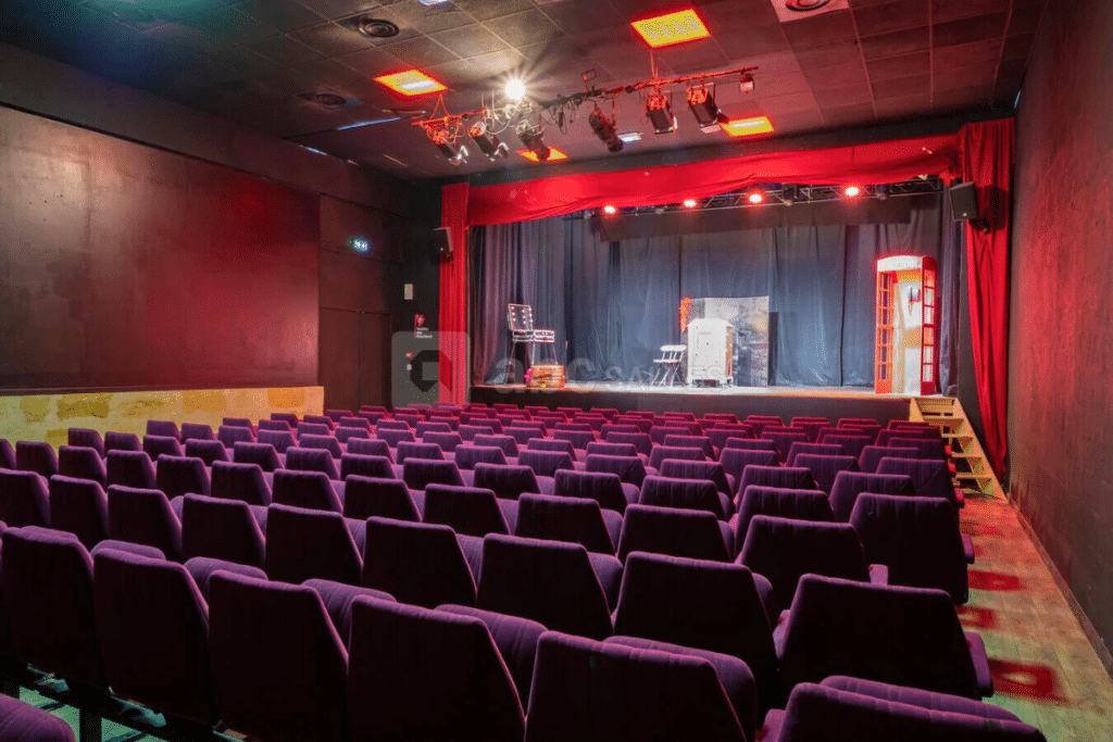Salle de théâtre vide avec rideaux rouges.