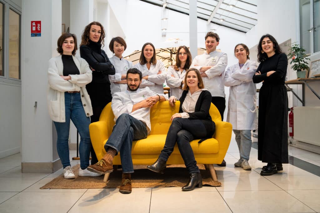 Équipe posant autour d'un canapé jaune.