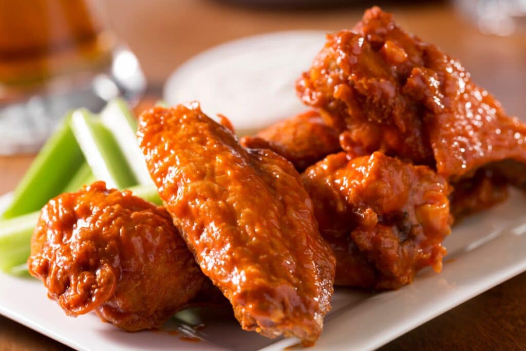 Ailes de poulet épicées sur assiette blanche.