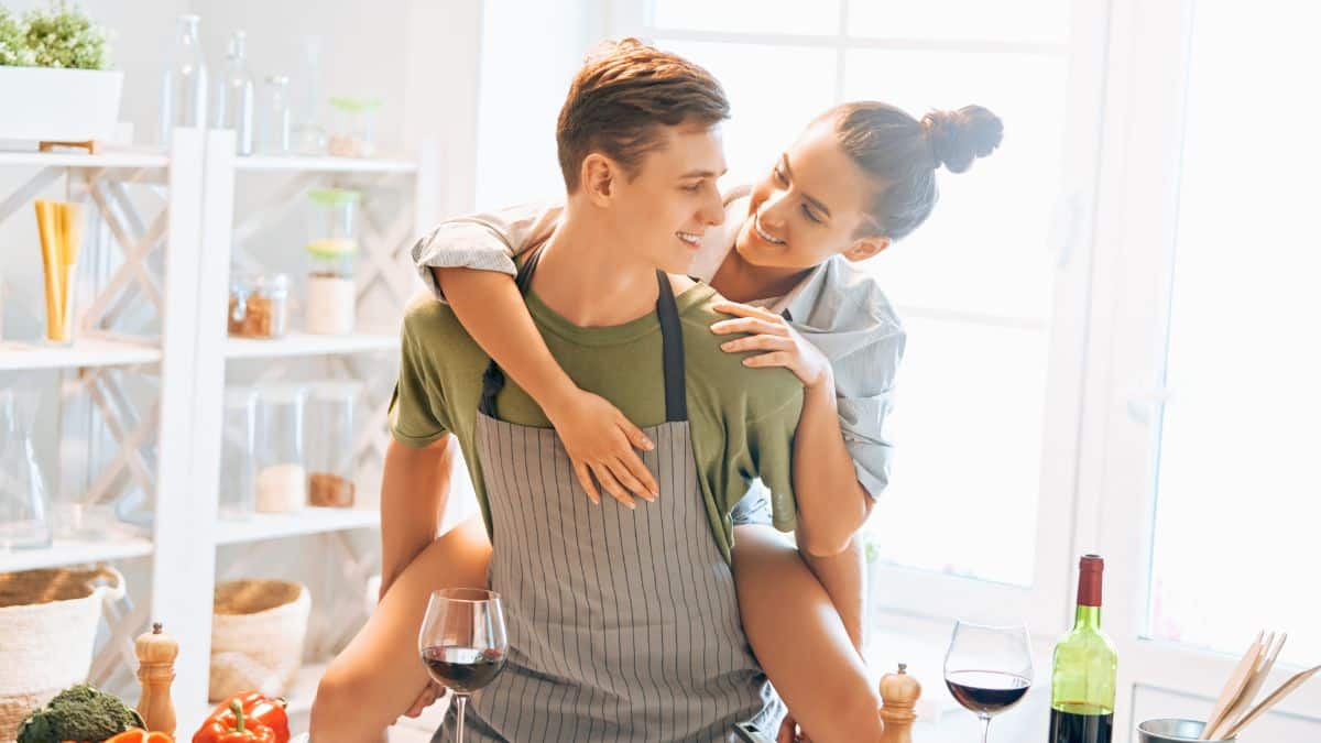 Couple souriant en cuisine avec vin.