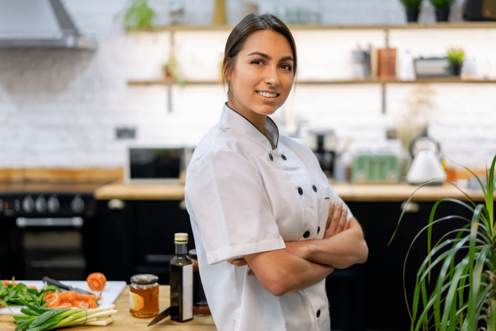 Chef dans une cuisine moderne, bras croisés.