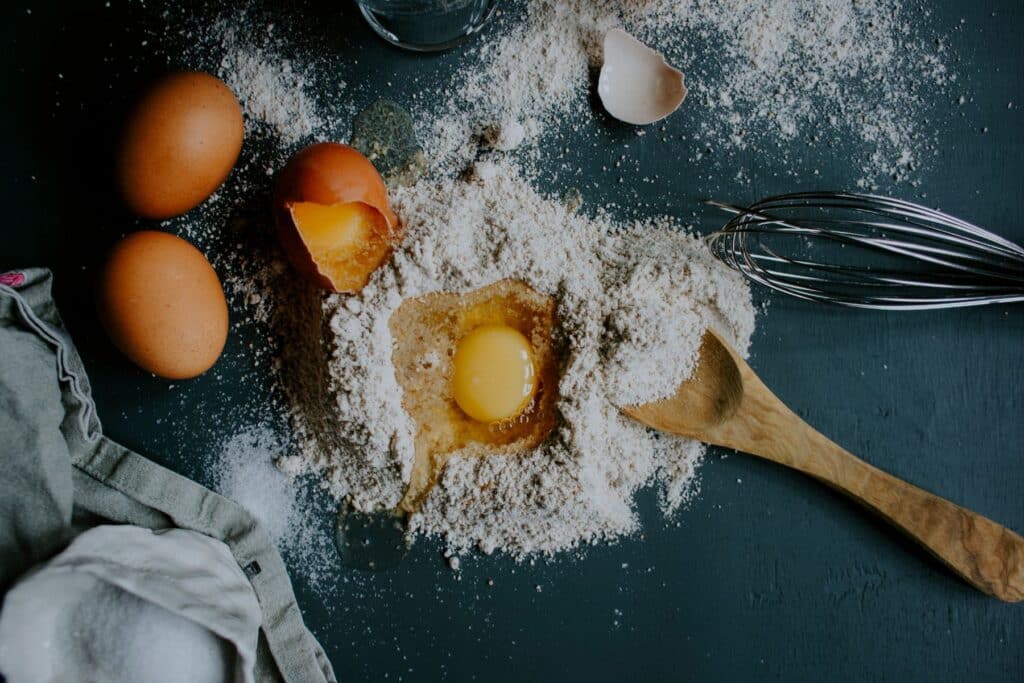 Préparation pâtisserie avec œufs et farine sur table.