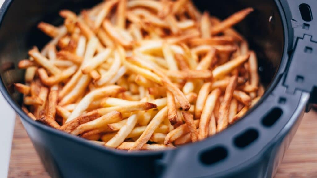 Frites dorées dans une friteuse noire.