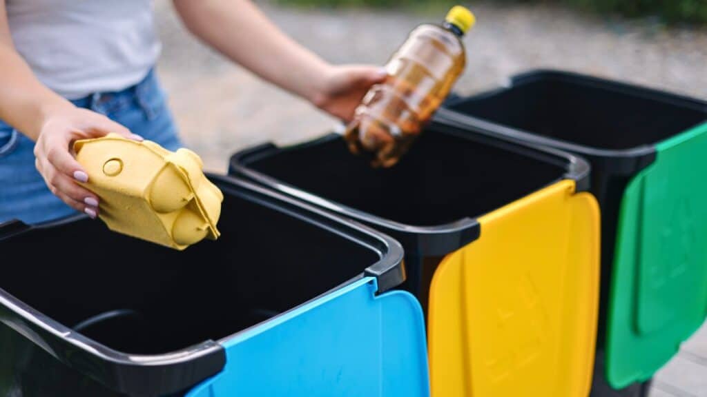 Personne trie des déchets dans des bacs colorés.