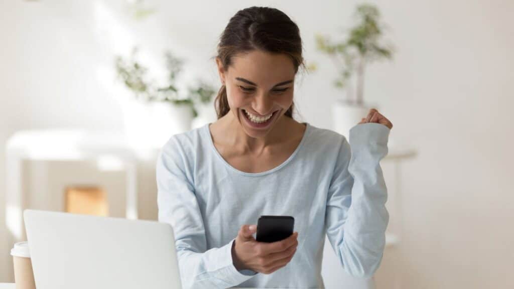 Femme souriante regardant son téléphone, victoire.