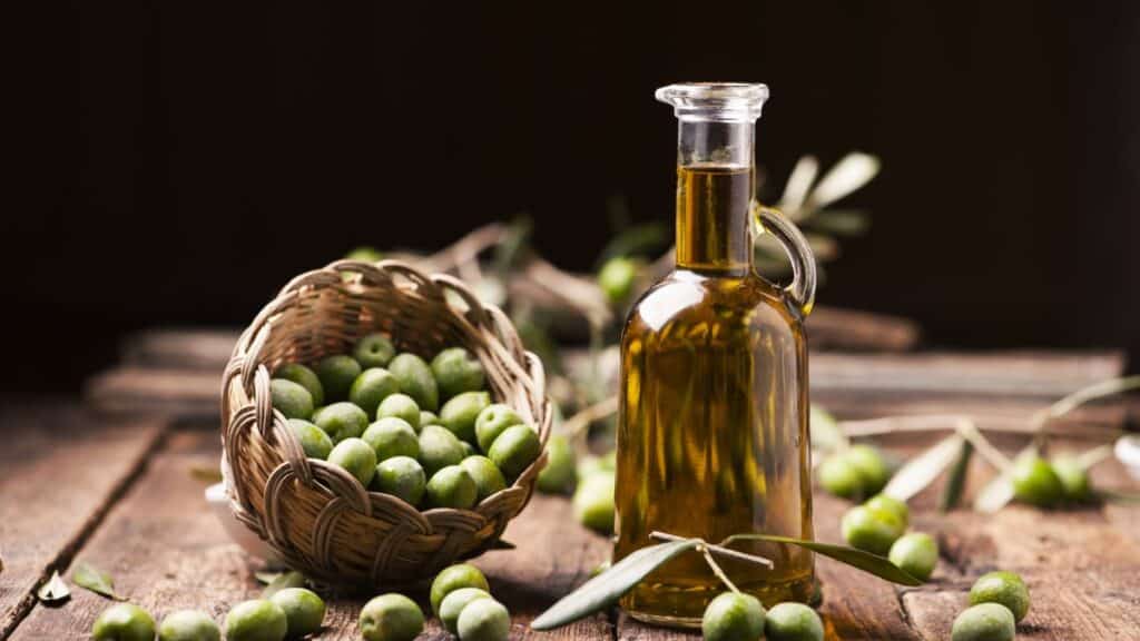 Bouteille d'huile d'olive et panier d'olives vertes.