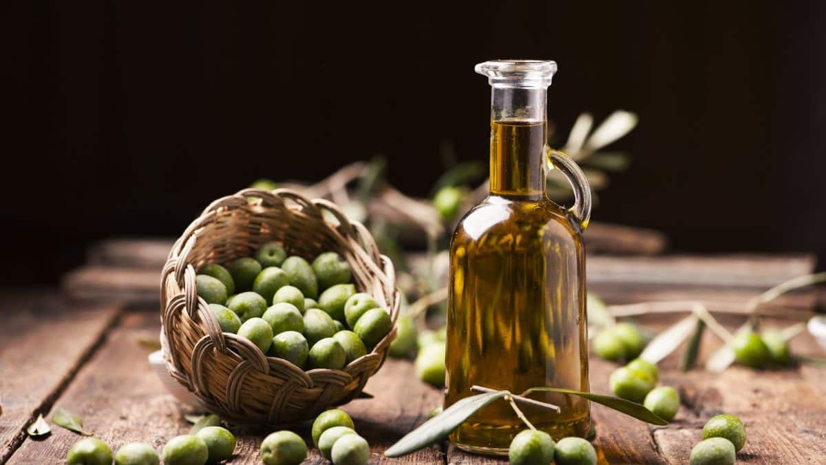 Bouteille d'huile d'olive et panier d'olives vertes.