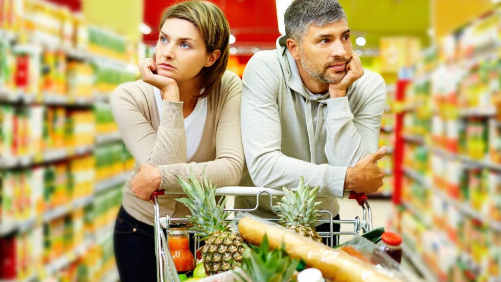 Couple ennuyé avec caddie supermarché.