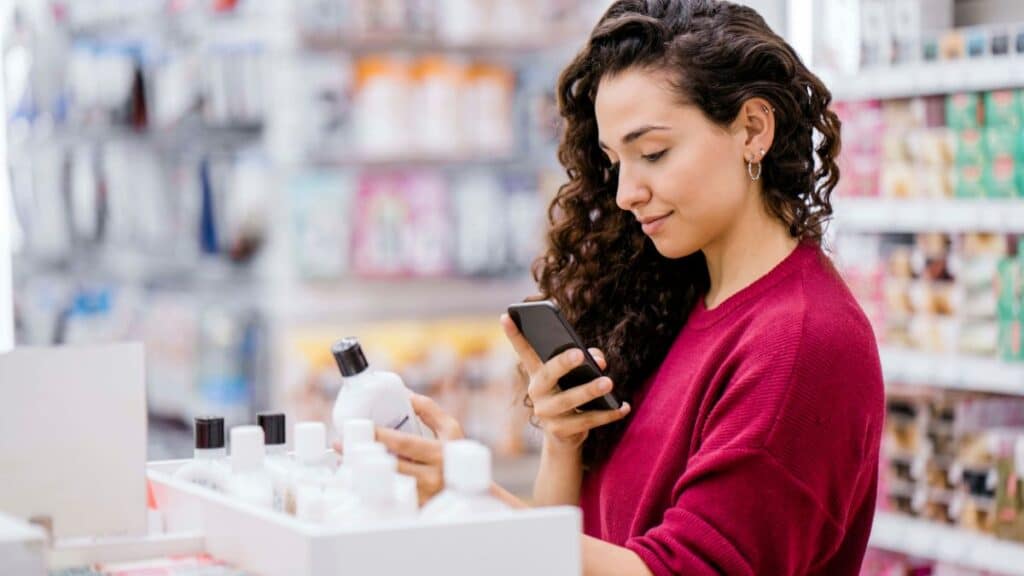 Femme choisissant un produit en magasin avec mobile.