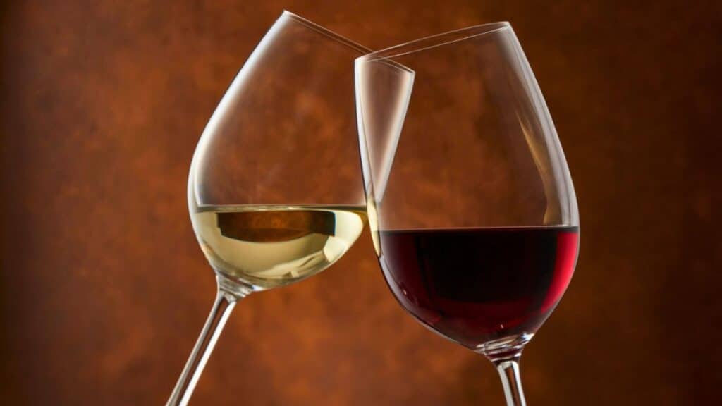 Deux verres de vin rouge et blanc s'entrechoquent.