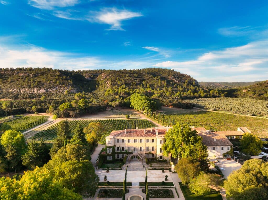 Manoir entouré de vignes et collines verdoyantes.