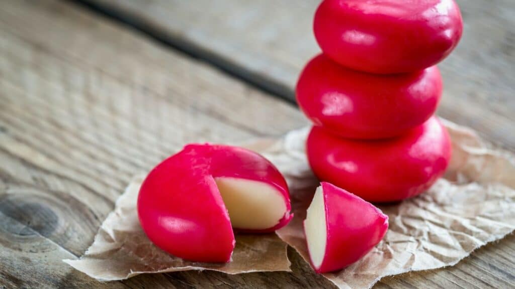 Fromages Babybel rouges empilés sur table en bois.