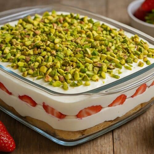 Tiramisu fraises pistache sur table en bois.