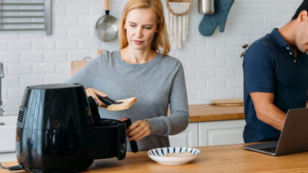 Personne utilisant une friteuse à air dans la cuisine.