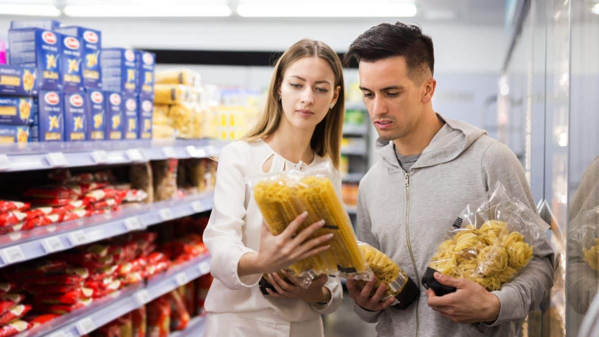 Couple choisissant des paquets de pâtes en magasin.