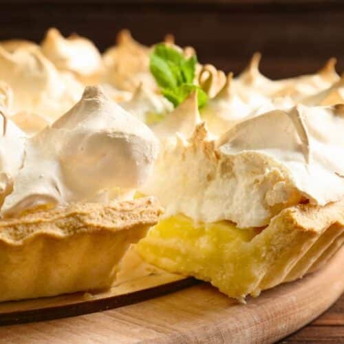 Tarte au citron meringuée sur assiette en bois.