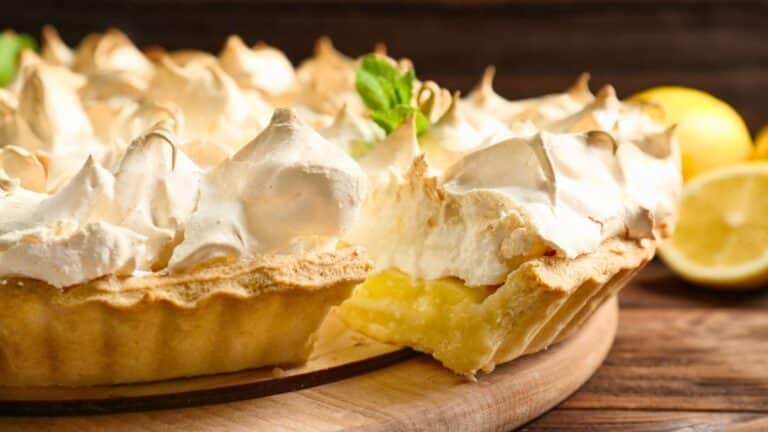 Tarte au citron meringuée sur assiette en bois.