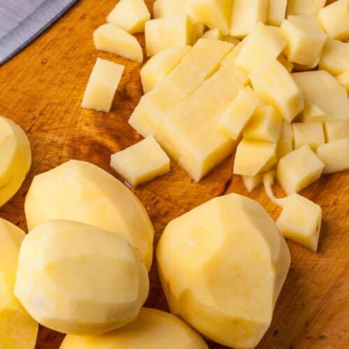 Pommes de terre pelées et coupées sur planche.