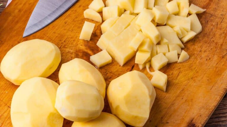 Pommes de terre pelées et coupées sur planche.